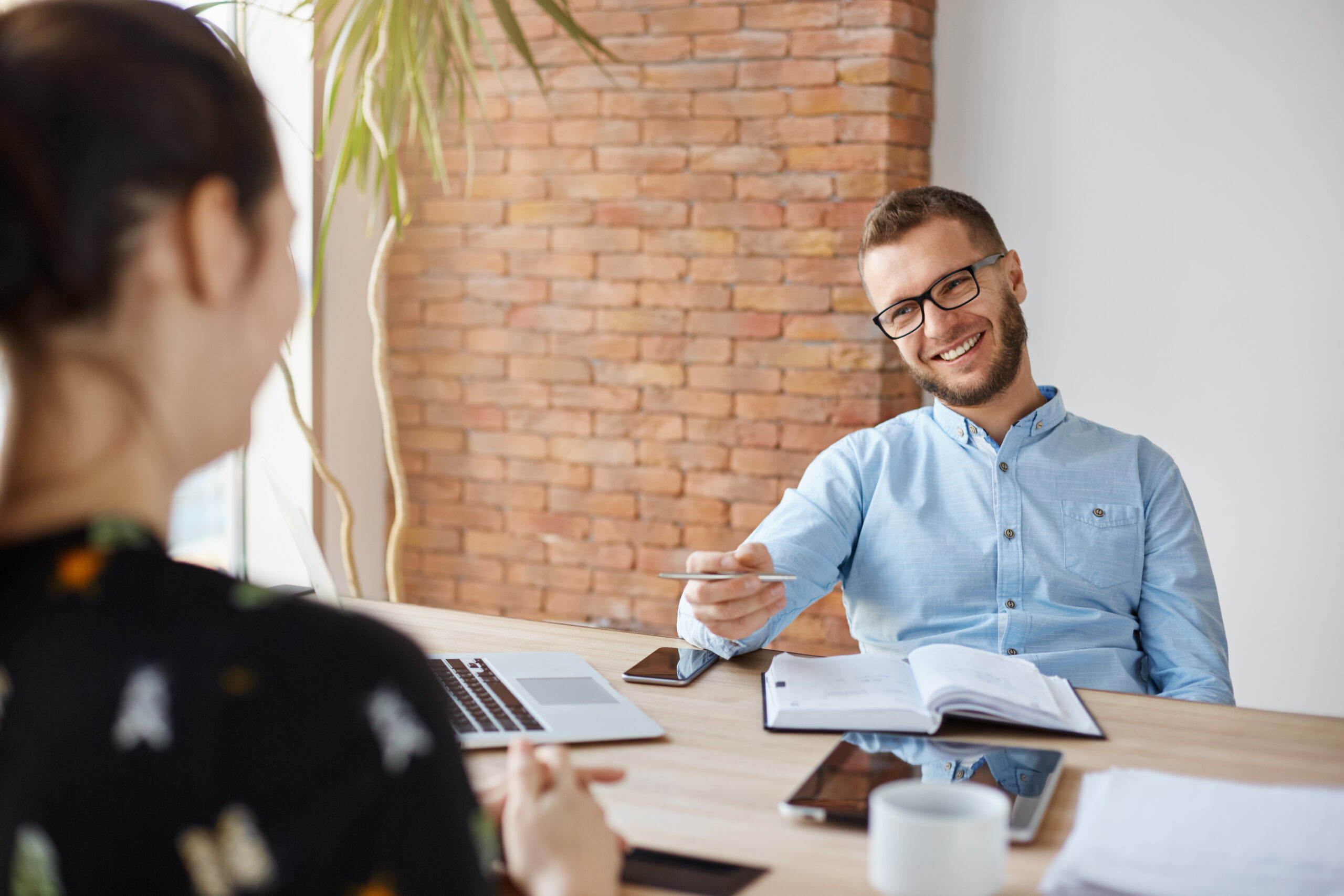 Business concept. Young dark-haired woman sitting in front of mature cheerful office manager on job interview, having relaxing talk about her experience and study degree
